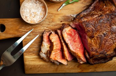 Siyah taş arka plan üzerinde ahşap doğrama tahtası üzerinde baharat ile Yağlı ızgara domuz biftek