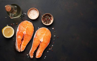 Siyah taş arka plan üzerinde baharat ve limon ile taze çiğ somon biftek