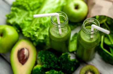 Gri arka planda sebze ve meyve ile Taze yeşil smoothie