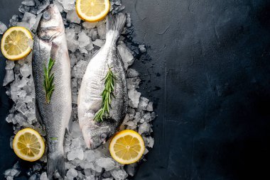 Soğuk ezilmiş buz yığını üzerinde limon dilimleri ve biberiye ile taze balık yakın görünümü