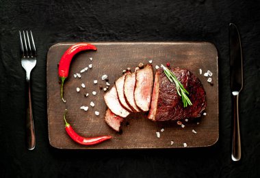 Siyah taş arka plan üzerinde baharat ve biberiye dal ile Taze ızgara biftek