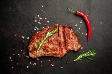 Siyah taş arka plan üzerinde baharat ve biberiye dalları ile Taze ızgara domuz biftek