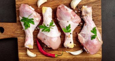 Ahşap doğrama tahtası üzerinde baharat, biber ve sarımsak ile Tavuk bacakları 