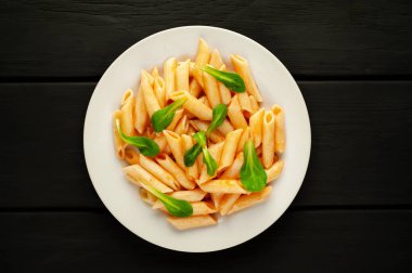 taş siyah arka plan üzerinde yeşil yaprakları ile servis domates soslu makarna