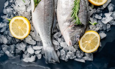 Soğuk ezilmiş buz yığını üzerinde limon dilimleri ve biberiye ile taze balık yakın görünümü