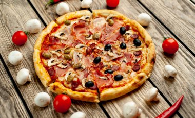 Ahşap arka plan üzerinde mantar, domates, zeytin ve jambon ile taze ev yapımı pizza