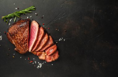 Orta-nadir taze sığır eti biftek siyah taş arka plan üzerinde biberiye dal ile servis