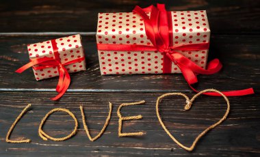 Hediye kutuları ve ahşap arka plan üzerinde ipliklerden yapılmış yazı aşk