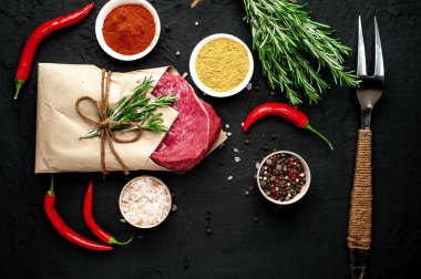 Siyah taş arka plan üzerinde baharat ile Çiğ taze biftek