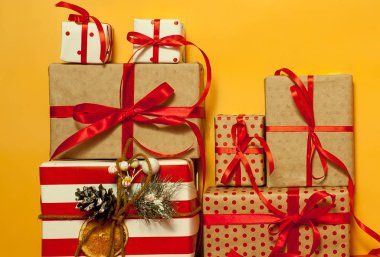 Parlak sarı arka plan üzerinde kırmızı yaylı hediye kutuları yığını 