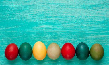 Parlak mavi ahşap arka planda renkli Paskalya yumurtası yığını