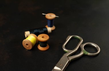 siyah arka plan üzerinde dikiş makaraları yığını ile terzi makasları 