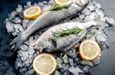 Soğuk ezilmiş buz yığını üzerinde limon dilimleri ve biberiye ile taze balık yakın görünümü