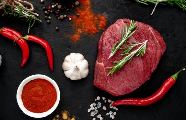 Siyah taş arka plan üzerinde baharat ile Çiğ taze biftek