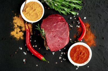 Siyah taş arka plan üzerinde baharat ile Çiğ taze biftek