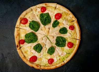 siyah taş arka plan üzerinde kiraz domates ve taze ıspanak yaprakları ile pizza