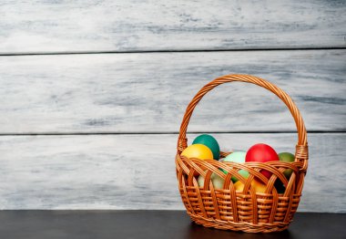 Beyaz ahşap arka plan üzerinde renkli Paskalya ile sepet yumurta