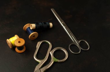 siyah arka plan üzerinde dikiş makaraları yığını ile terzi makasları 