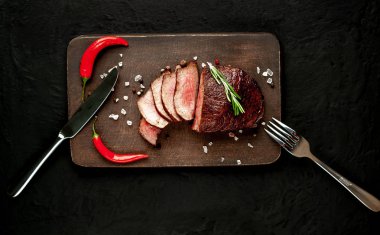 Siyah taş arka plan üzerinde baharat ve biberiye dal ile Taze ızgara biftek