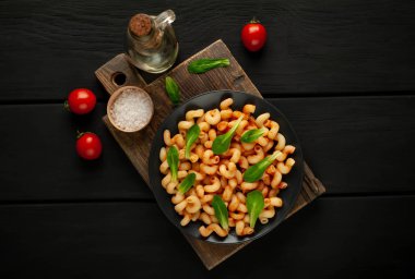 taş siyah arka plan üzerinde ahşap doğrama tahtası üzerinde domates soslu makarna