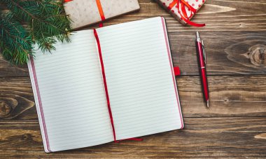 Eski ahşap arka plan üzerinde kırmızı yay ve boş defter ile hediye kutuları yığını 