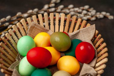 Siyah taş arka planda renkli Paskalya yumurtaları ve kedi söğüt dalları ile sepet