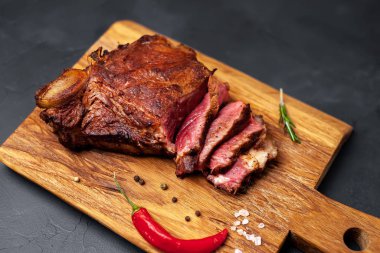 Siyah taş arka plan üzerinde doğrama tahtası üzerinde baharat ve biber ile Yağlı ızgara domuz biftek