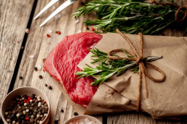 ahşap arka plan üzerinde zanaat kağıt sarılmış baharat ile biftek 