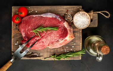 Ahşap doğrama tahtasında biberiye ve domates ile taze çiğ biftek 