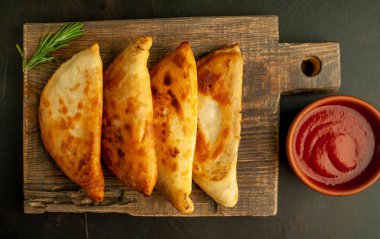 Ahşap doğrama tahtası üzerinde domates soslu Geleneksel Latin Amerika kızarmış empanadas 
