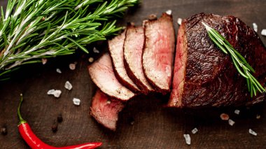 Siyah taş arka plan üzerinde baharat ve biberiye dalları ile Taze ızgara biftek