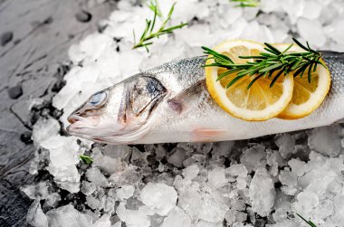Soğuk ezilmiş buz yığını üzerinde limon dilimleri ve biberiye ile taze balık yakın görünümü