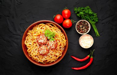 köfte, parmesan peyniri, biber dilimleri ve taş arka plan üzerinde maydanoz dalları ile İtalyan spagetti makarna 