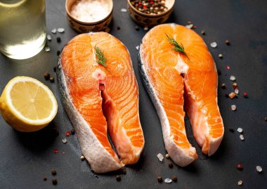 Siyah taş arka plan üzerinde baharat ve limon ile taze çiğ somon biftek