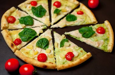 siyah taş arka plan üzerinde kiraz domates ve taze ıspanak yaprakları ile pizza