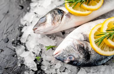 Soğuk ezilmiş buz yığını üzerinde limon dilimleri ve biberiye ile taze balık yakın görünümü