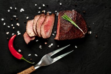 Siyah taş arka plan üzerinde baharat ve biberiye dal ile Taze ızgara biftek