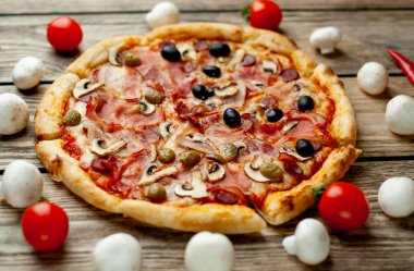 Ahşap arka plan üzerinde mantar, domates, zeytin ve jambon ile taze ev yapımı pizza