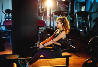 Genç sporcu kadın boş spor salonunda kas çalıştırıyor.  