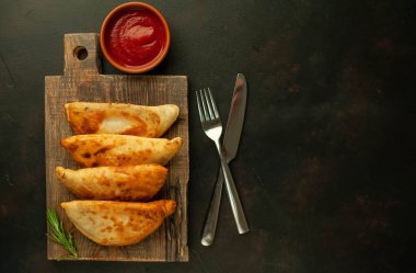 Ahşap doğrama tahtası üzerinde domates soslu Geleneksel Latin Amerika kızarmış empanadas 