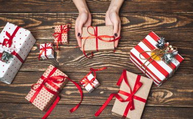 Eski ahşap arka plan üzerinde kırmızı yay ile kadın elleri dekorasyon hediye kutuları 