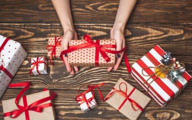 Eski ahşap arka plan üzerinde kırmızı yay ile kadın elleri dekorasyon hediye kutuları 