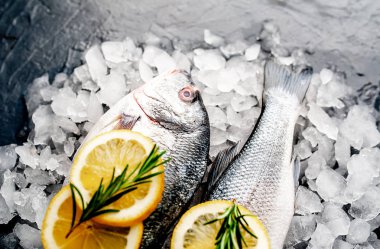 Soğuk ezilmiş buz yığını üzerinde limon dilimleri ve biberiye ile taze balık yakın görünümü