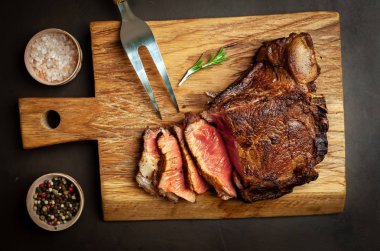 Siyah taş arka plan üzerinde ahşap doğrama tahtası üzerinde baharat ile Yağlı ızgara domuz biftek