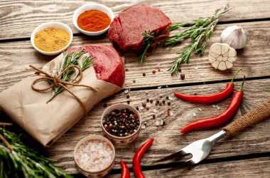 Ahşap arka planda renkli baharatlar ile Çiğ biftek