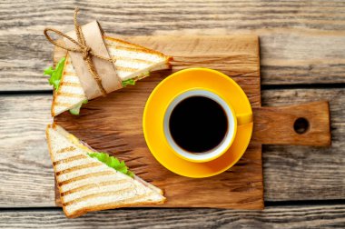 Jambon ve peynir ile taze ızgara sandviç ahşap doğrama tahtası üzerinde kahve fincan ile servis