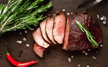 Siyah taş arka plan üzerinde baharat ve biberiye dalları ile Taze ızgara biftek