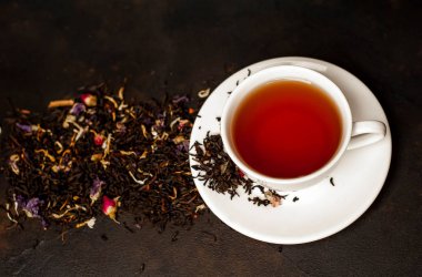 siyah arka plan üzerinde çiçek demlemek yığını ile taze çay fincan