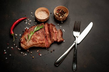 Siyah taş arka plan üzerinde baharat ve biberiye dal ile Taze ızgara domuz biftek
