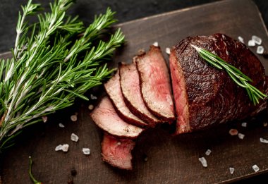 Siyah taş arka plan üzerinde baharat ve biberiye dalları ile Taze ızgara biftek